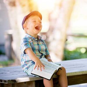 boy laughing with bible on lap