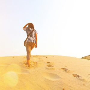 woman walking in sand with footprints