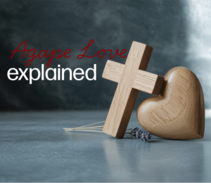wooden cross leaning on wooden heart "Agape Love explained"